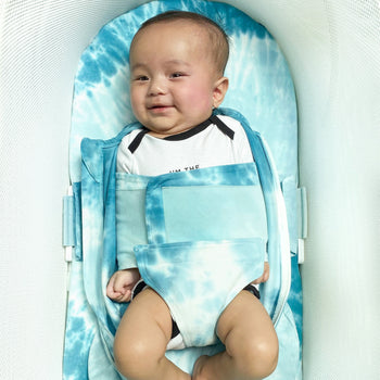 Baby in SNOO bassinet with Blue Tie-Dye SNOO Sheet swaddled in unzipped Blue Tie-Dye SNOO Sack