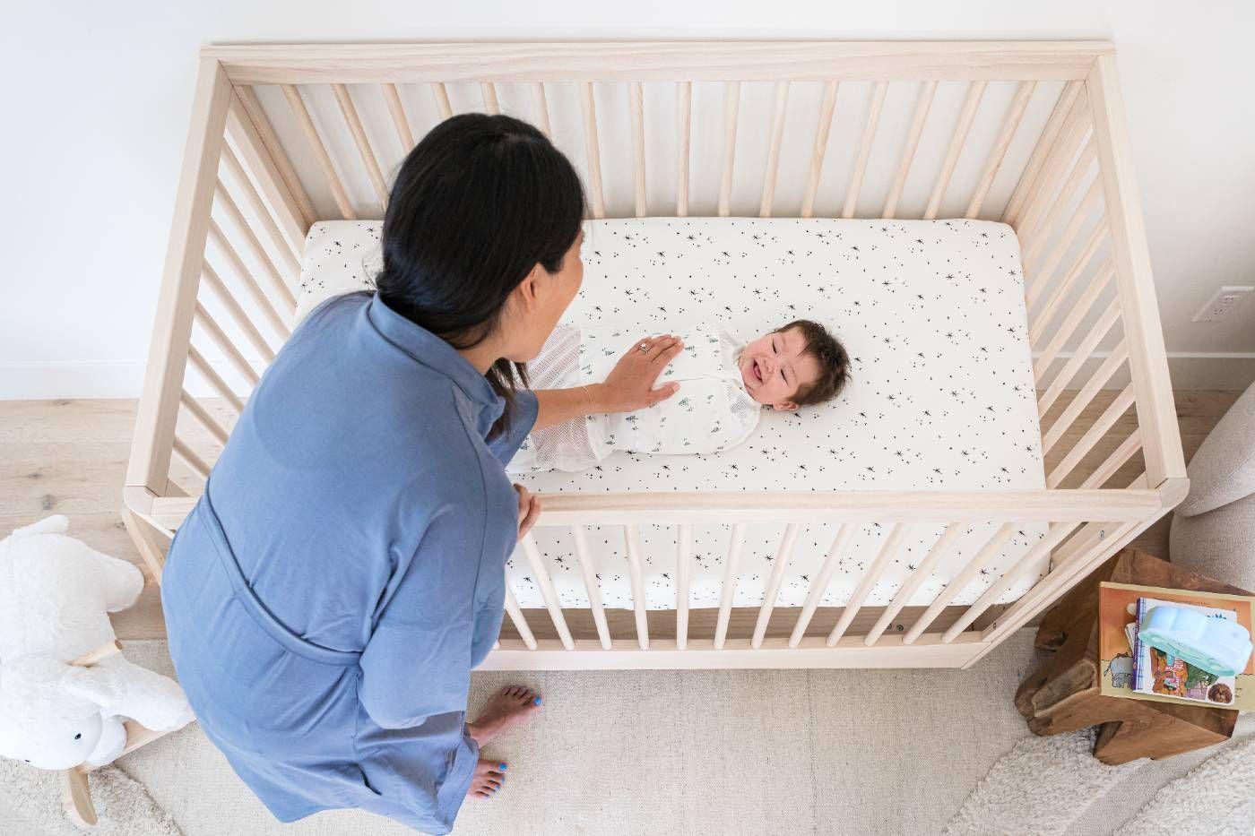 Mom touching baby, happily laying on the DreamBreeZzz cot mattress