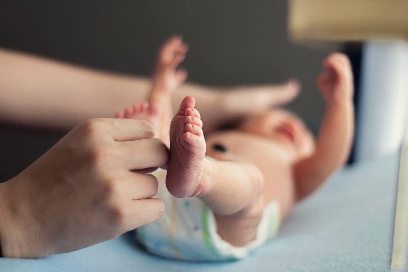parent changing newborn in nappy first poop