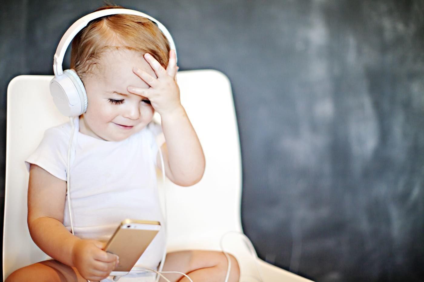 A toddler listens to a podcast on headphones.