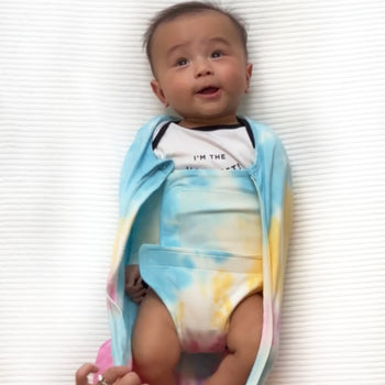 Baby unzipped in rainbow tie-dye Sleepea swaddled with arms down