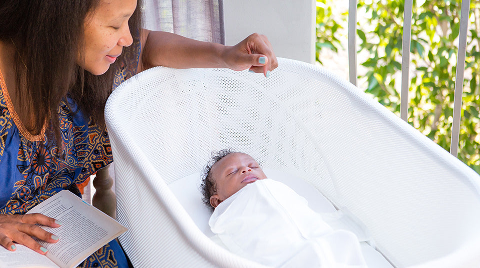 A woman checking on her baby sleeping inside a Snoo Smart Bassinet